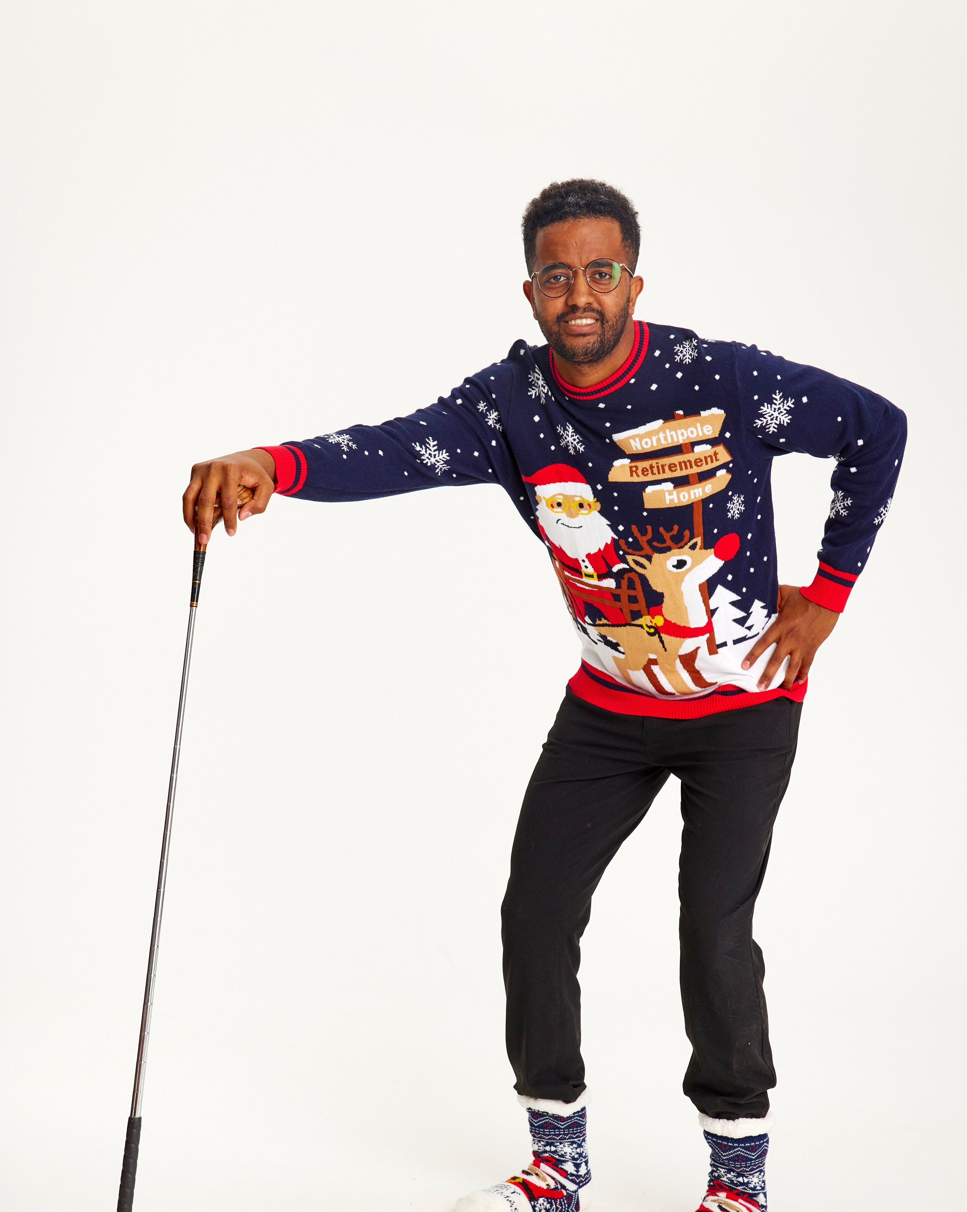 En mand poserer som en person med rygproblemer og er iført en julesweater.